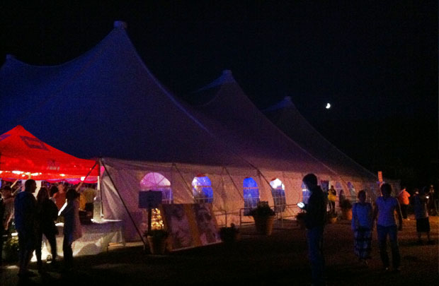 The moon shines above the big tent.